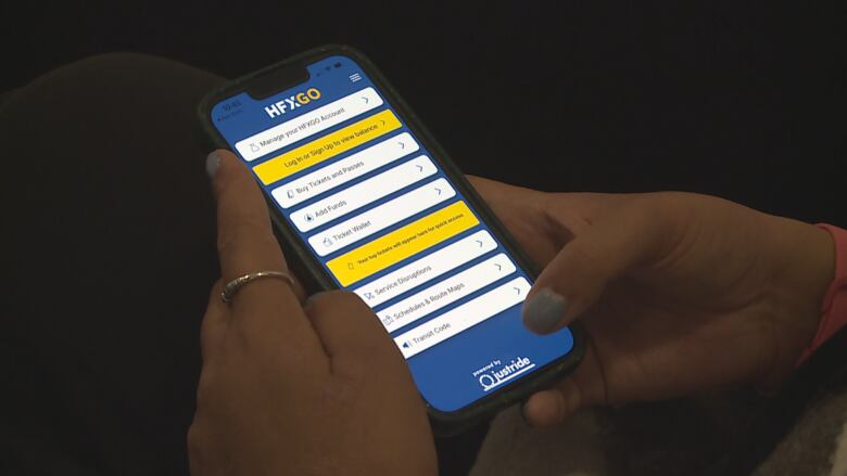 A woman's hands can be seen, using the HFXGO transit app. 