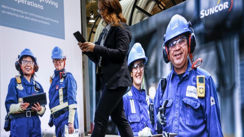 Delegates walks past an image of oil workers at the World Petroleum Congress  in Calgary, Monday, Sept. 18, 2023.THE CANADIAN PRESS/Jeff McIntosh