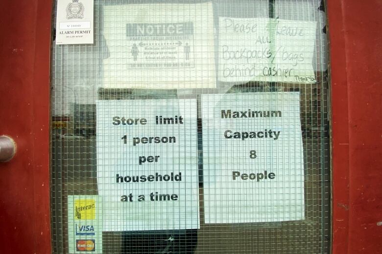 Signs in the window of a store's door read 