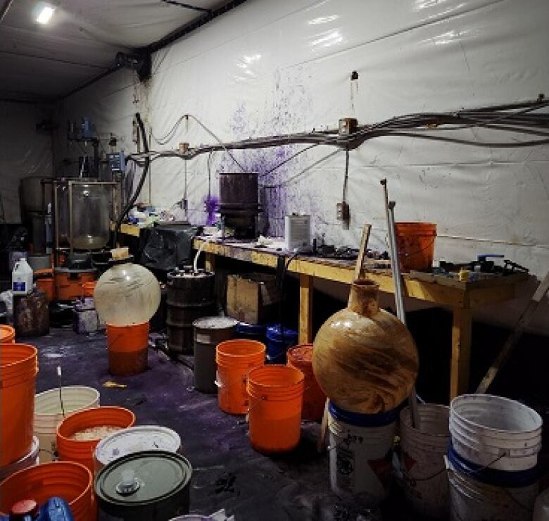 a cluttered and dirty room full of large chemistry equipment and buckets of substances