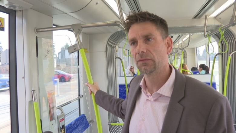 A man wearing a pink shirt and brown blazer holding a neon green pole