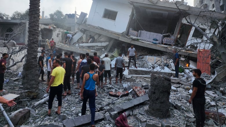 People look for survivors in the rubble of a destroyed building. 