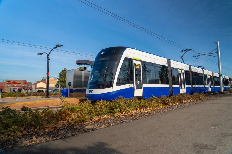 The front half of a blue and white train parked at a train station