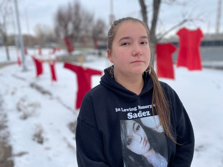 A girl in a black hoodie with a woman's photo and the words 