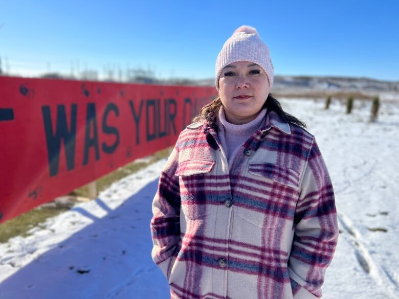 A woman in a plaid jacket stands outside.