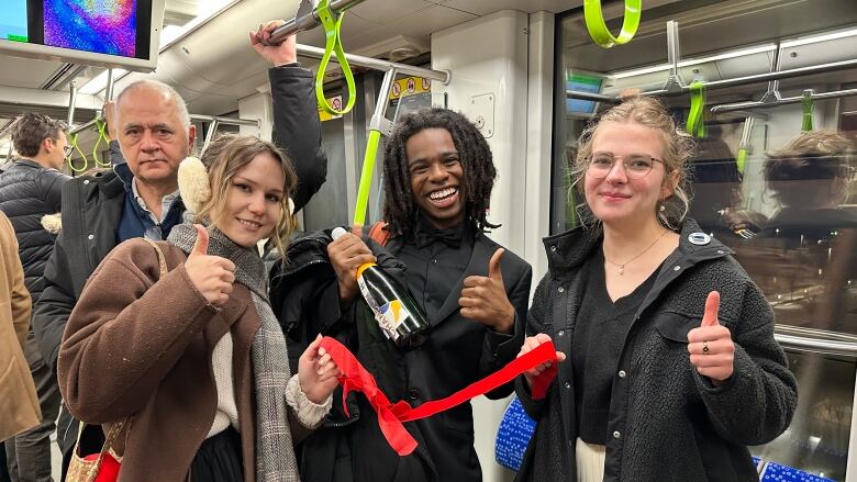 two women and two men holding a bottle and red ribbon smiling for the camera