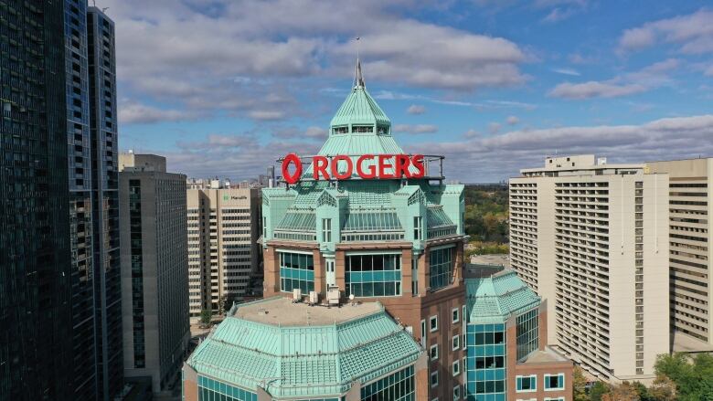 A drone shot takes a picture of a large skyscraper with the words 'Rogers' on it.