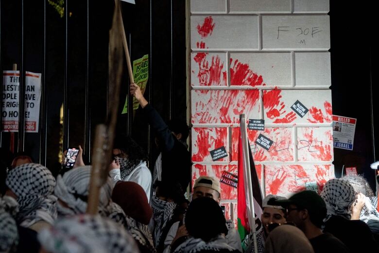 Demonstrators leave red hand prints on a surface.