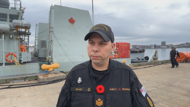 A man in a petty officer second class uniform speaks to the camera.