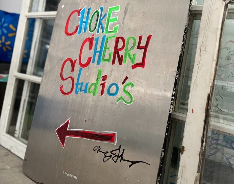 A big sign with colourful letters saying Choke Cherry Studio's, and a red arrow pointing to the left underneath the text.