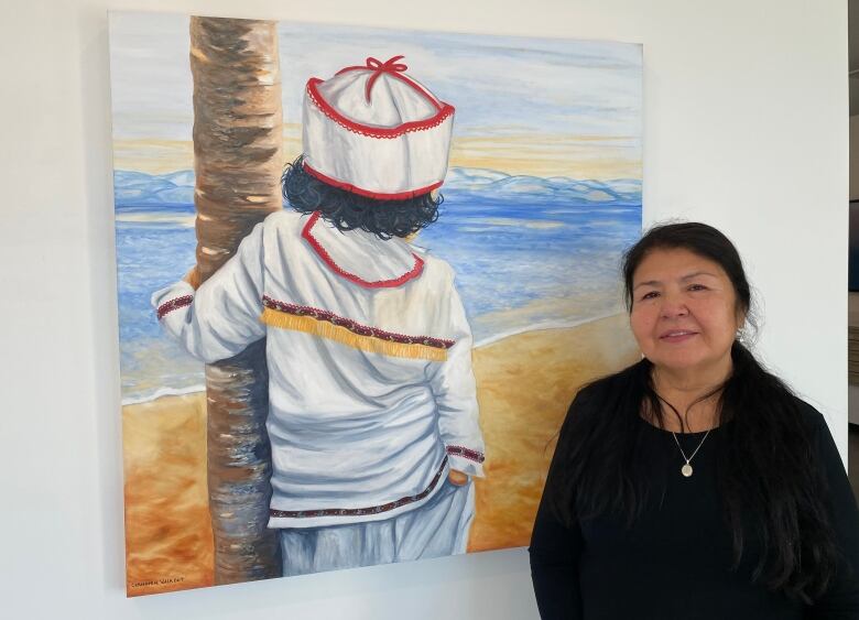 A woman stands in front of a painting of a young boy, his back to the viewer.