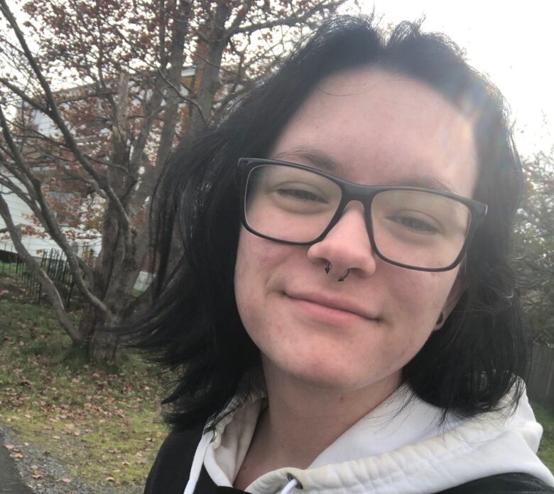 Selfie of smiling a teenage boy with shoulder-length black hair, glasses and a septum piercing.