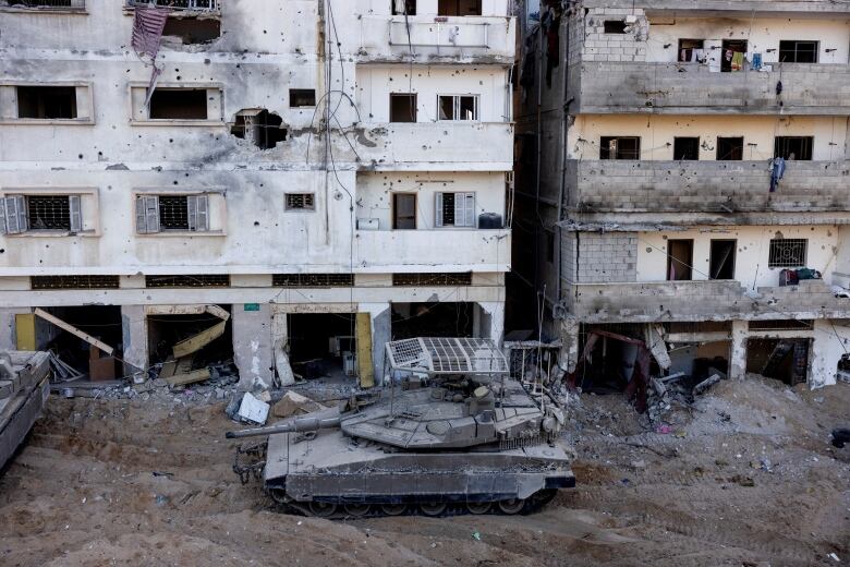 An Israeli tank drives through rubble, next to buildings, in the northern Gaza Strip.