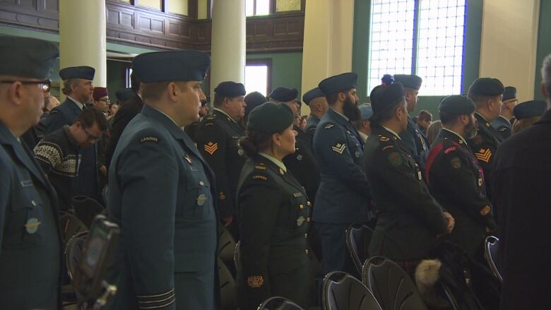 A crowd of people wearing uniforms stand facing forward.