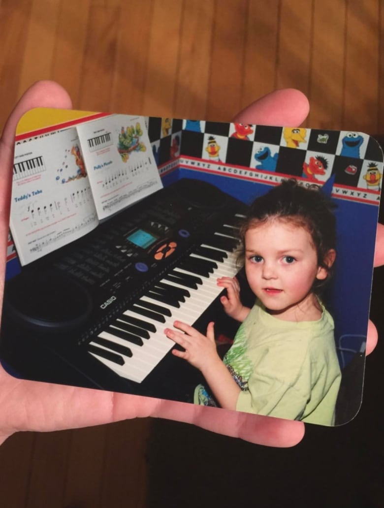 A girl sits at an electric keyboard, looking at the camera. 