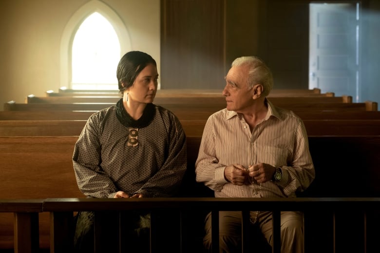 A female actor and male director sit together in church set for the film Killers of the Flower Moon.