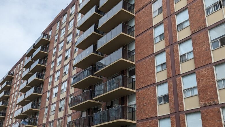 The exterior of a multi-level brick apartment building has balconies.