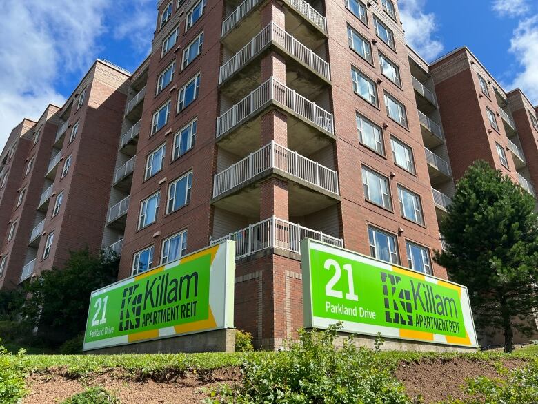 A multi-story brick apartment building with two signs outside saying 