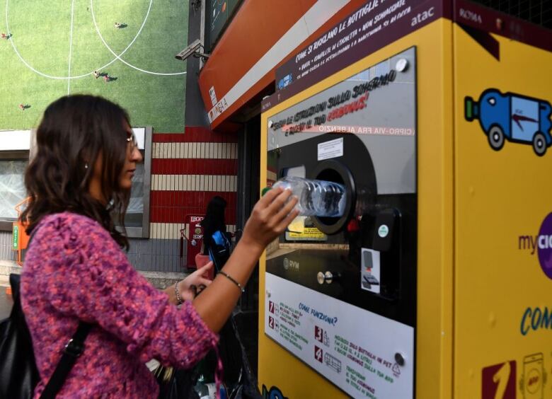 A woman trades a plastic bottle for transit credit at a reverse vending machine 