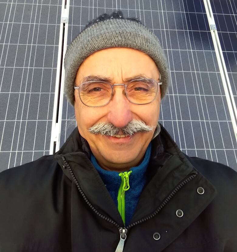 A selfie of a man with a gray moustache and glasses, wearing a toque.