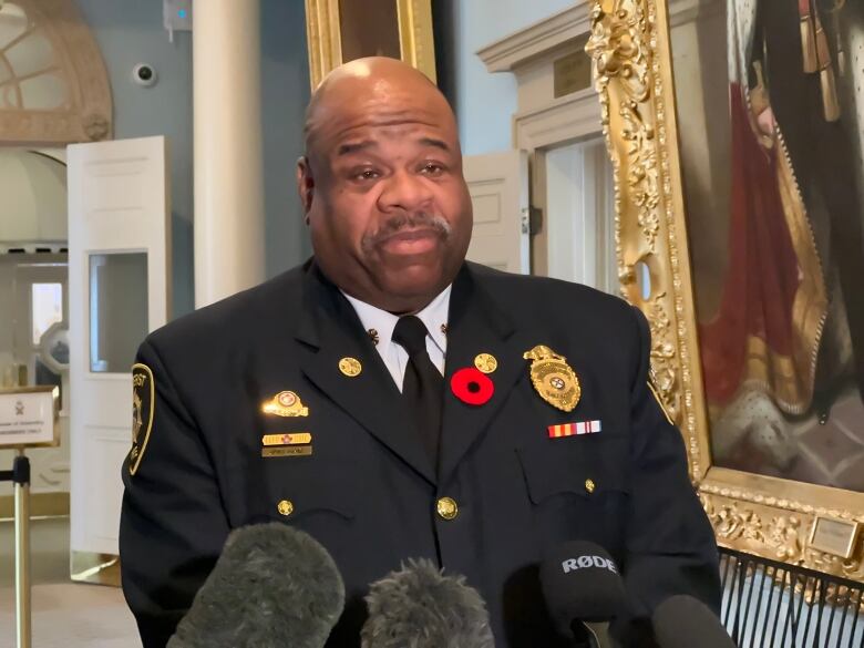 A man wearing a black suit that is decorated with badges. 