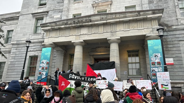 People stand outside with signs.