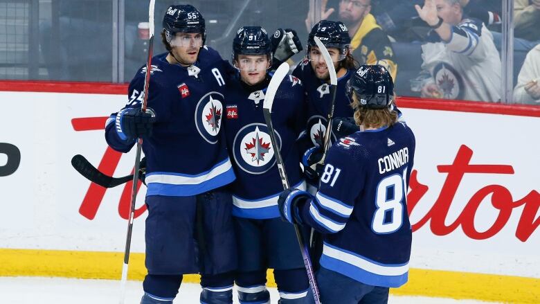 A group of hockey players in blue and white uniforms celebrate together.