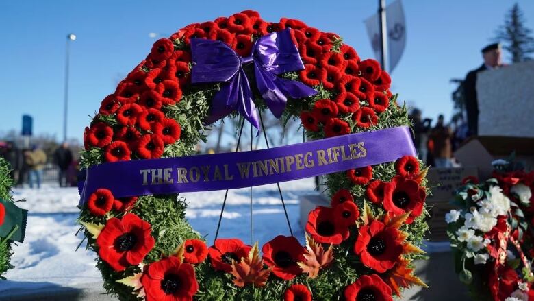 A Remembrance Day wreath with a banner that says The Royal Winnipeg Rifles stands in the snow.