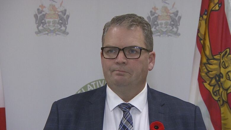 A politician stands in front of a microphone waiting to answer questions from reporters.