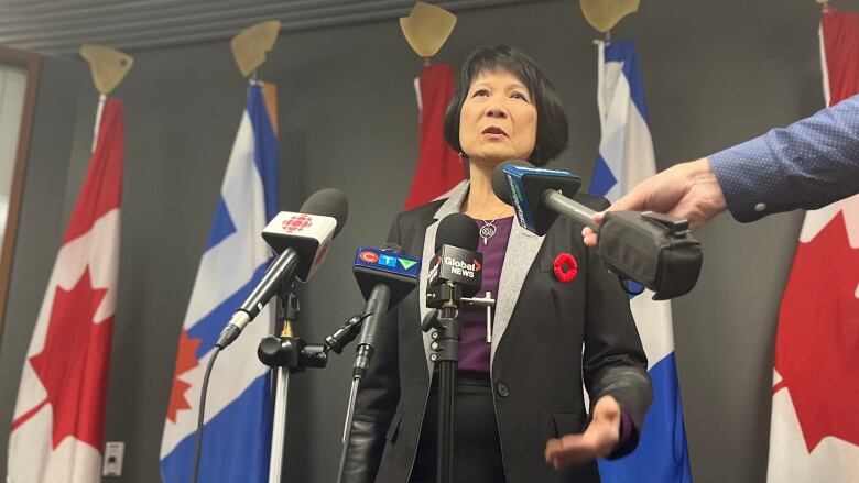 Chow speaks to reporters in front of a row of microphones.