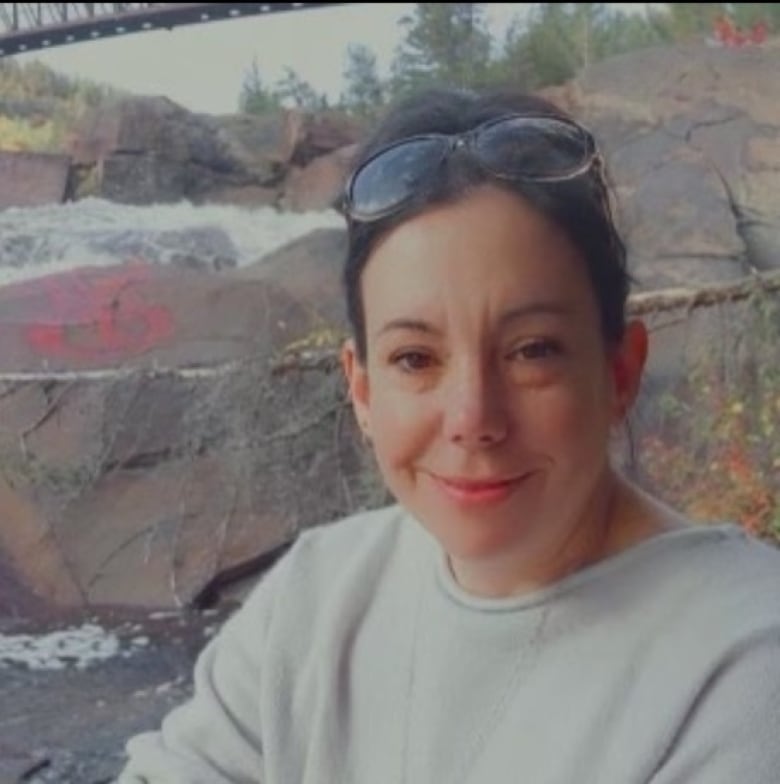 A woman with dark hair wearing a grey sweater.