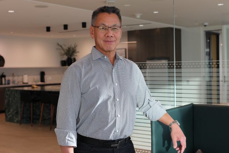 A man in glasses and a blue button down is pictured inside a downtown Calgary office.