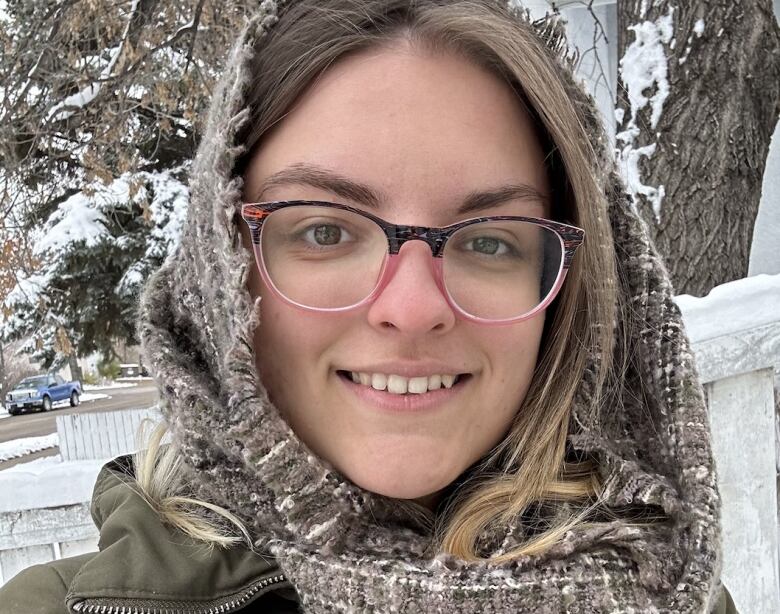 A woman with glasses smiles in the snow.