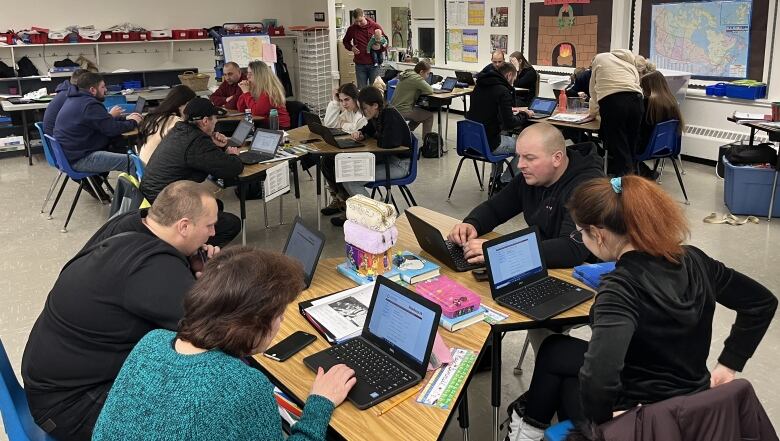 People sit at desks on a computer.