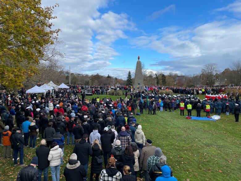 a cenotaph with hundreds of people gathered around. 