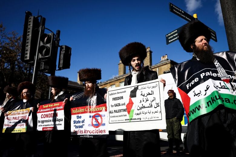 Members of the Ultra-Orthodox Jewish community hold placards in support of Palestinians.