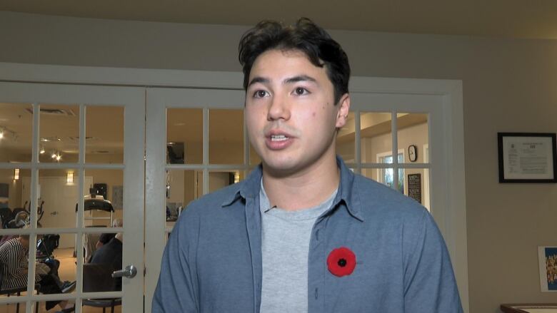 a young man in a blue shirt with a red poppy pin