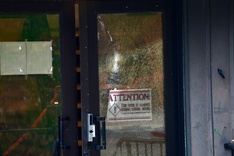 The shattered glass of a school door after it was shot at. 