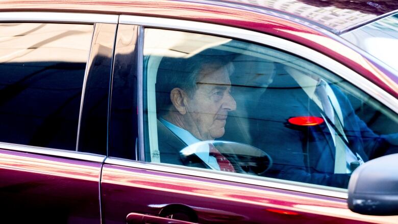 A person is seen in the passenger seat of a car.