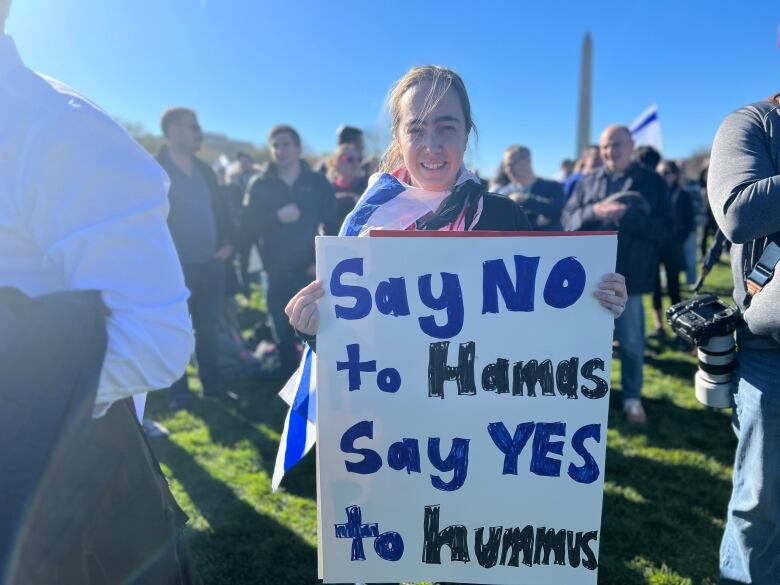 Woman in front of Washington Monument holds sign that says: 