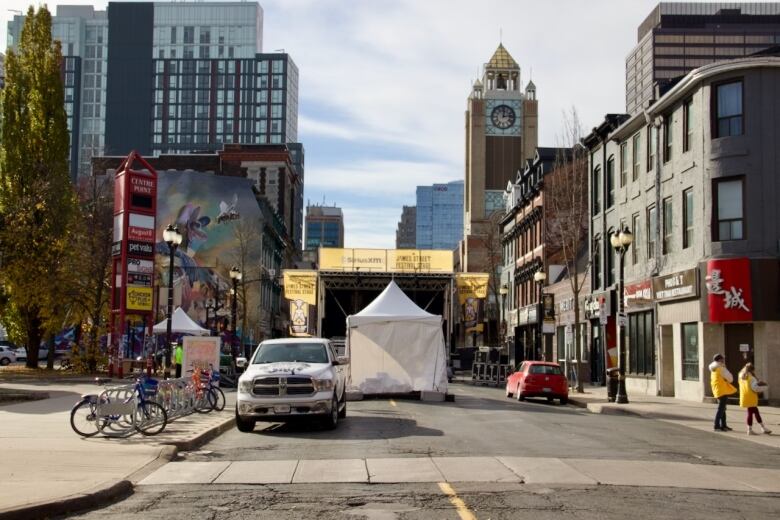 Trucks and a tent sit in an empty street while scaffolding for a stage is erected at the end.