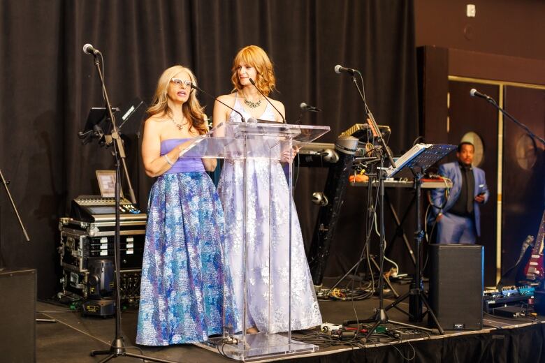 Teresa Tiano, left, and Katy Kosyachkova, right, both stomach cancer survivors, are seen on stage speaking at an event.