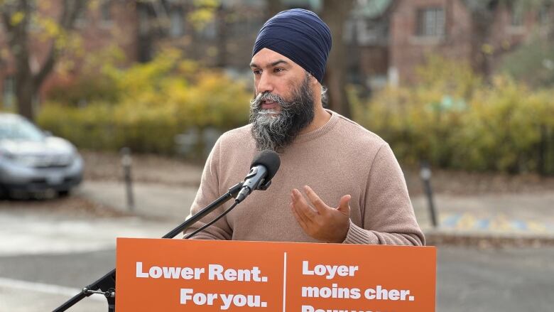 NDP Leader Jagmeet Singh stands at a podium speaking to reporters