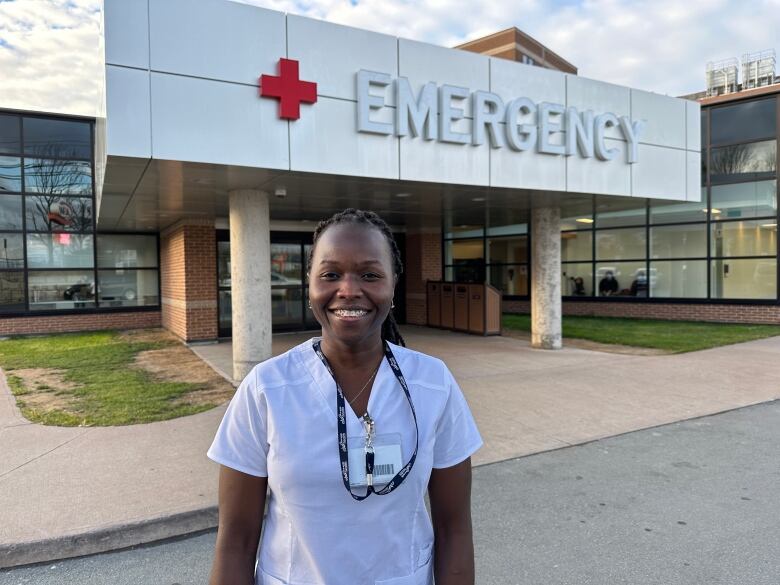 A nurse stands outside the Aberdeen Hospital in New Glasgow beneath a big emergency entrance sign.