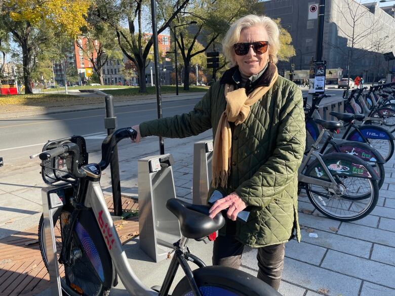 A woman holds a bicycle.