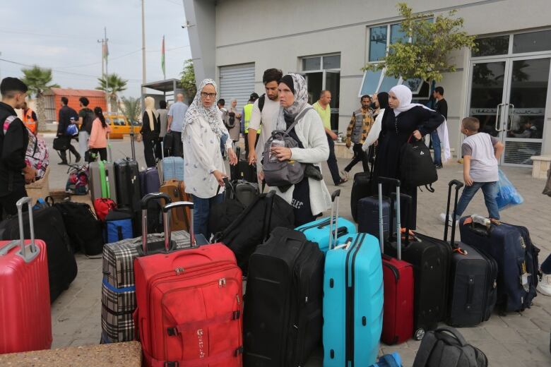 People with suitcases waiting outside. 