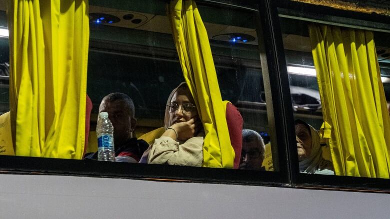 A woman looks out the window of a bus. 