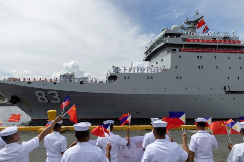 People wave flags at approaching ship