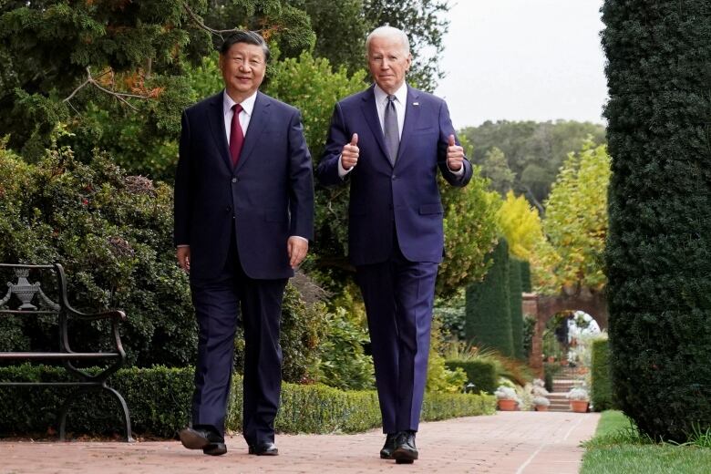 Leaders walking outdoors. Biden offers thumbs up