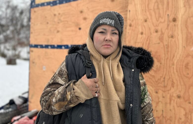 Woman stands in front of plywood structure